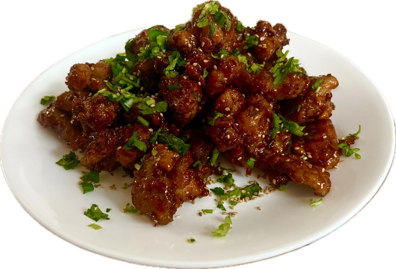 Bite-sized Korean crispy chicken in a glossy glaze, topped with sesame seeds and green herbs